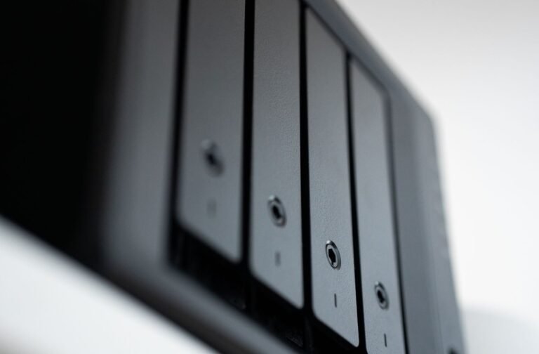 A silver laptop and white external hard drive on a modern office desk.